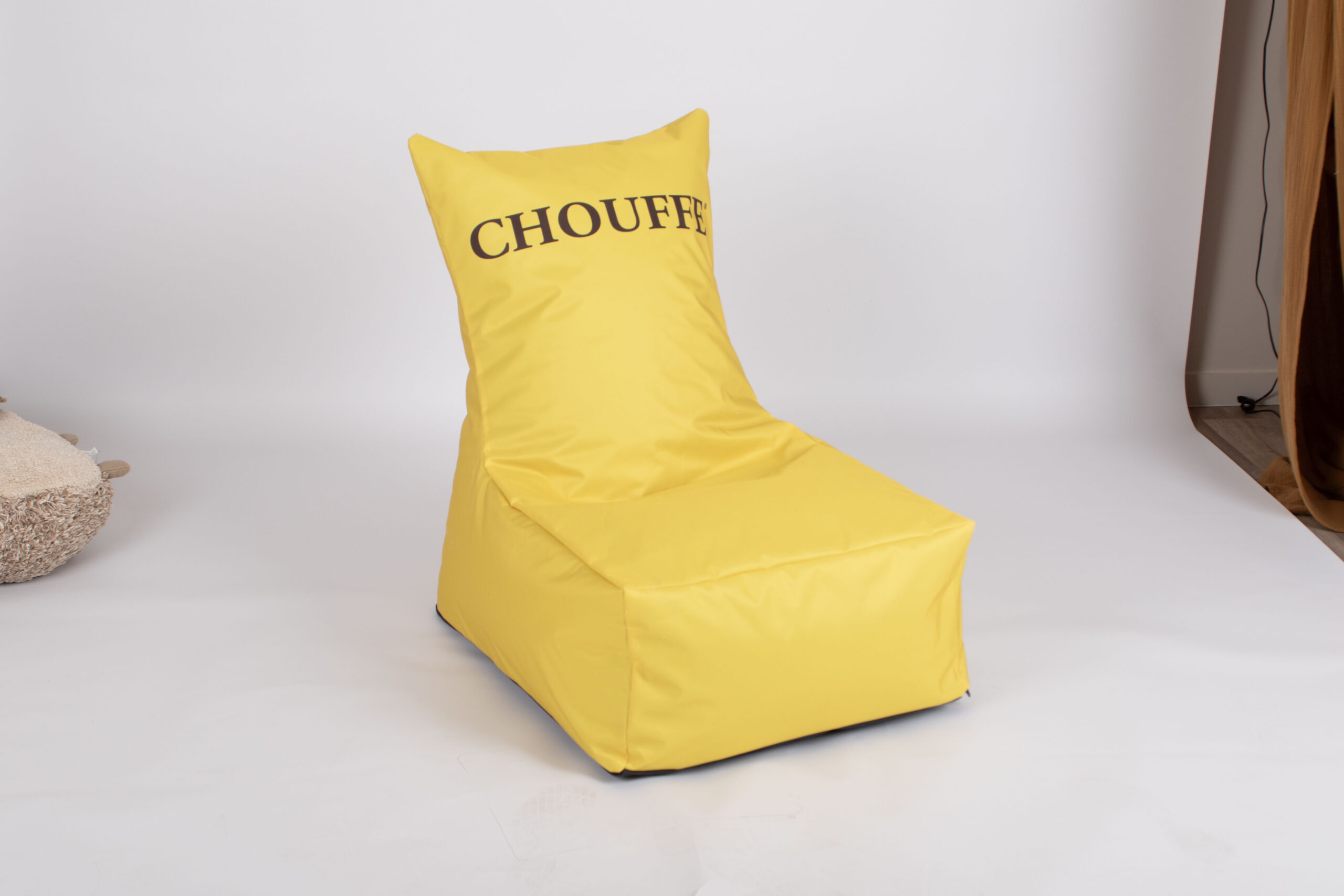 Żółta pufa reklamowa typu „bean bag” z oparciem i ciemnym logotypem CHOUFFE na jasnym tle.