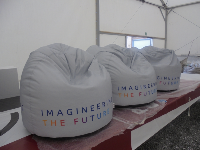 Jasnoszare pufy reklamowe typu „bean bag” z nadrukiem hasła „Imagineering The Future” w kolorowej czcionce.