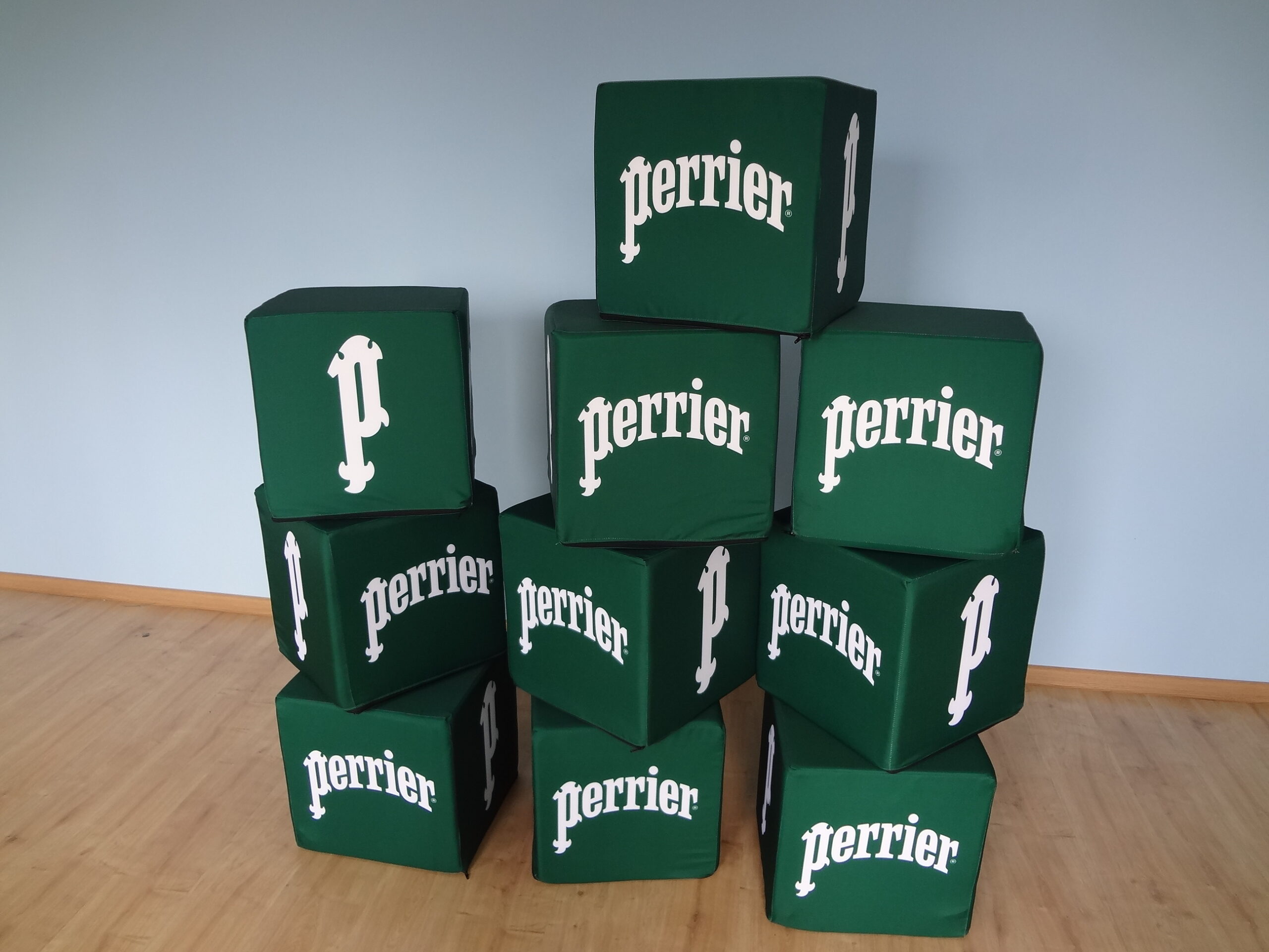 Zestaw zielonych puf reklamowych w kształcie kostek z logotypami marki Perrier.