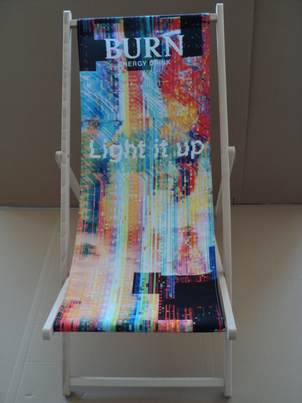 Drewniany leżak plażowy z kolorowym, abstrakcyjnym wzorem, logotypem Burn Energy Drink oraz hasłem "Light it up".