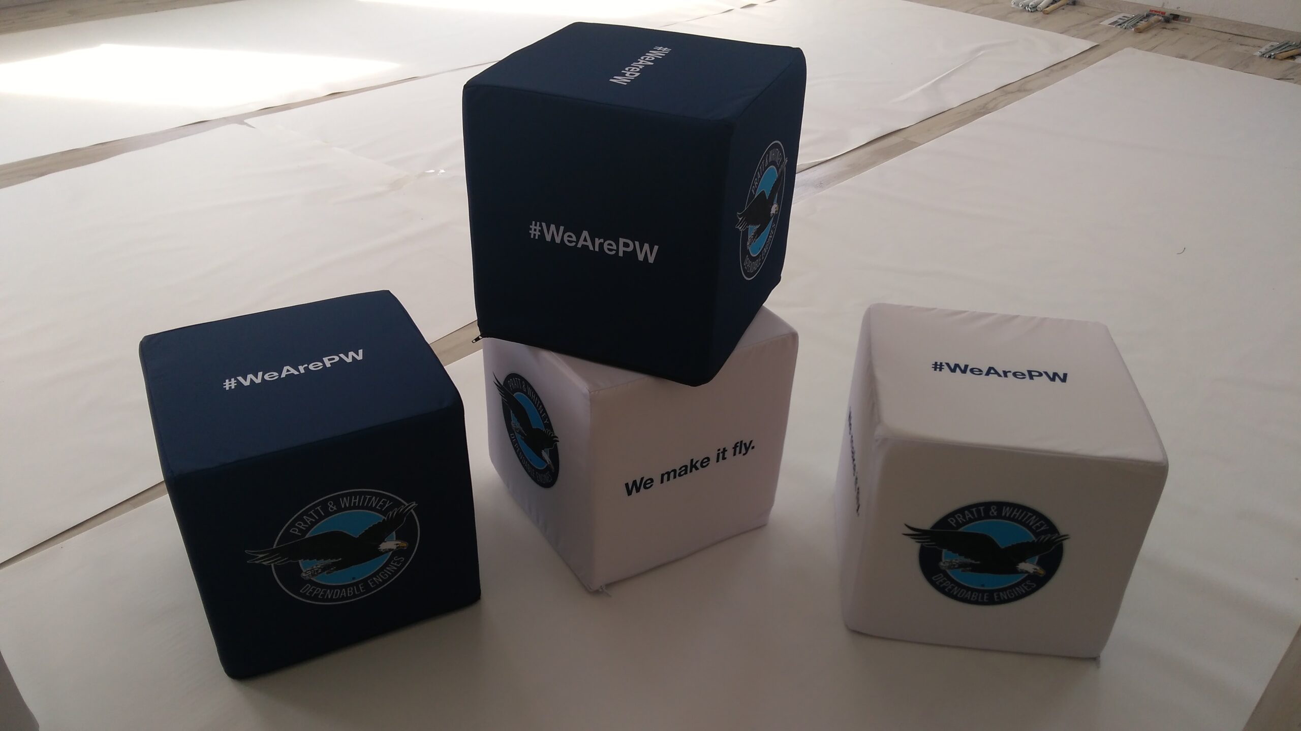 Zestaw puf reklamowych w kształcie kostek z logotypami Pratt & Whitney oraz hasłem #WeArePW.