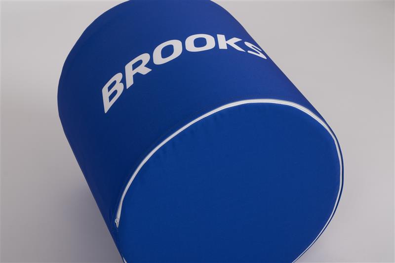 Niebieska okrągła pufa reklamowa z białym logotypem marki Brooks.
