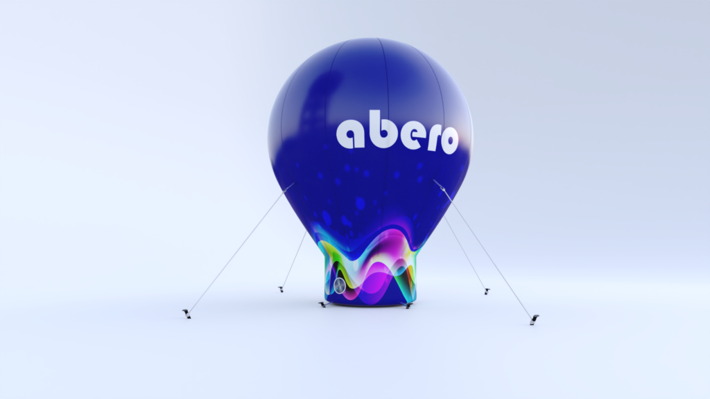 Pneumatyczny balon reklamowy w kształcie kropli z logo "abero" na granatowym tle z kolorowymi akcentami; balon jest stabilizowany za pomocą odciągów i posiada zintegrowany system nadmuchowy, przeznaczony do celów promocyjnych i eventowych.
